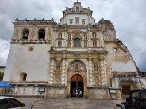 an old church with a tower and a building at El Portal de los Pasos in Antigua Guatemala
