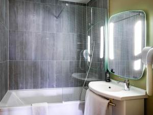 a bathroom with a tub and a sink and a mirror at ibis Saint Gratien - Enghien-Les-Bains in Saint-Gratien +57 photos