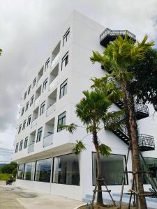 a white building with palm trees in front of it at UPMOON Hotel Chalong Phuket in Ban Suan