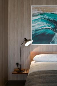 a bedroom with a bed with a lamp and a painting at Breathtaking Sydney Harbour Views from Stylish Harbourside Studio in Sydney