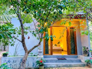 a house with yellow walls and stairs and a tree at The Mirror Wall Sigiriya in Sigiriya