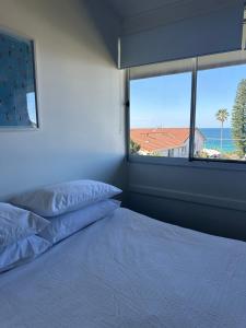 Un dormitorio con una cama y una ventana grande. en One Mile Horizon - Beach House, en Forster