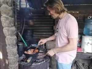 a man cooking food in a pan on a grill at Home coraizone in Cobán