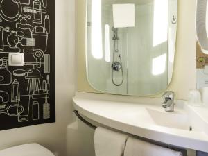 a bathroom with a sink and a mirror at Ibis Aéroport Bâle Mulhouse in Saint-Louis