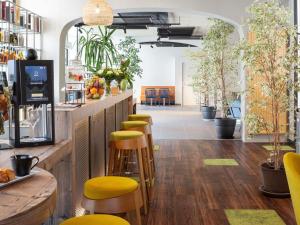 Una fila de taburetes en un bar con plantas. en Mercure Millau, en Millau