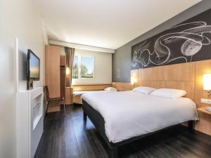 a hotel room with a large bed and a tv at ibis Issoire in Issoire