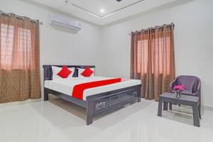 a bedroom with a bed and a chair at Hotel O Ayyappa Residency in Kondapur