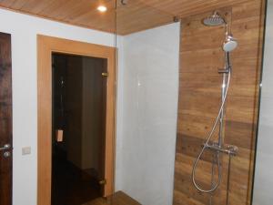 a shower in a bathroom with a wooden wall at Yellow Center Holiday Home in Pärnu