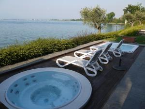 una piscina con sedie e vasca da bagno di Hotel Acquaviva Del Garda a Desenzano del Garda