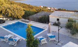 a swimming pool with chairs and a house and the ocean at Holiday Home Bepo in Sevid