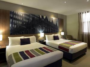 a hotel room with two beds and a painting on the wall at Grosvenor Hotel Adelaide by Accor in Adelaide +31 photos