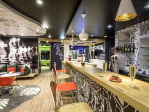 un restaurante con un bar con sillas naranjas en ibis Perpignan Sud Saint Charles, en Perpiñán