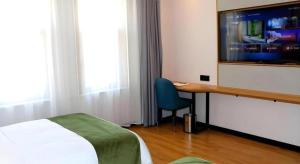Un dormitorio con una cama, un escritorio y un televisor. en Green Tree Inn Express Inner Mongolia Ulan Qab High-Speed Railway Station, en Ulanqab