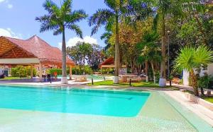 a swimming pool with palm trees and a house at Paraíso Liverte Cancún 603 in Cancún