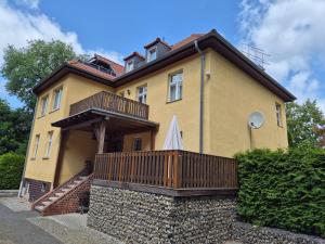 a large yellow house with a wooden deck at Haus am Wendsee in Brandenburg an der Havel +6 photos