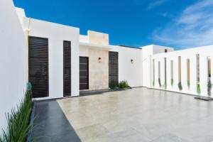 a white house with black shutters and a patio at Luxury home-heated Pool-2bedroom in Cancún