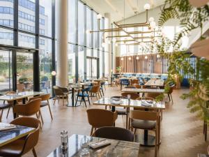 a restaurant with tables and chairs and windows at Novotel Le Havre Centre Gare in Le Havre