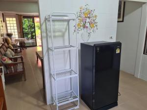 a black refrigerator with three shelves next to a living room at Sawaddee Holland in Ban Phlong Takhe +3 photos