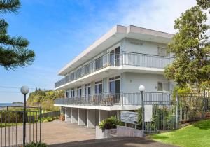 a white building with balconies and a fence at Bombo Breeze in Kiama
