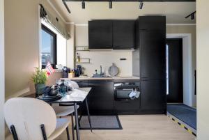 a kitchen with black cabinets and a table with chairs at Premium Studio by Arctic Seasons - A Cozy Luxury Escape at the Top of Tromsø in Tromsø +10 photos