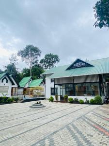 a white building with a green roof and a courtyard at Regalia Wayanad in Kalpetta