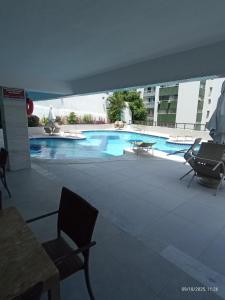 a large swimming pool in a building with chairs at Apart Atlantic City Service Ondina in Salvador