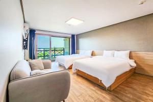 a hotel room with two beds and a couch at Whinstone Hotel & Resort in Jeju +37 photos