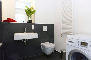 a bathroom with a toilet and a sink and a washing machine at Spacious Studio Apartment Friedrichshain in Berlin +3 photos