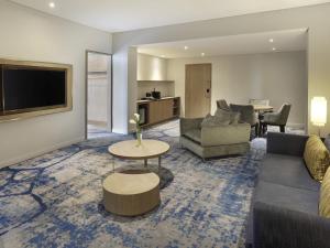 a living room with a couch and a tv at Novotel Jakarta Mangga Dua Square in Jakarta