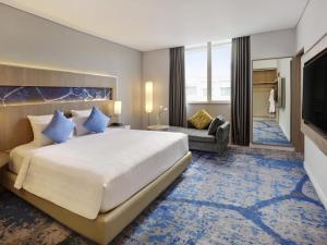 a hotel room with a large bed and a television at Novotel Jakarta Mangga Dua Square in Jakarta