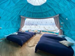 a room with four beds in a blue tent at Glamp Sora Furano in Nakafurano