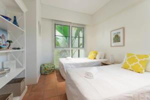 ein weißes Zimmer mit zwei Betten und einem Fenster in der Unterkunft No 3 @ The Hill Apartments in Port Douglas + 12 Fotos