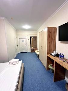 a hotel room with a bed and a desk and a television at Afsona Hotel in Bukhara