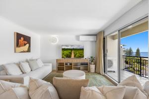 a living room with a white couch and a balcony at Oceanfront 3-Bed Retreat with Pool-Steps to Beach in Caloundra