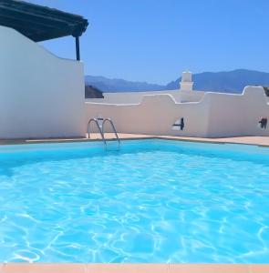 a swimming pool in a villa with blue water at Dragon View - Oceanfront Apartment Faro de Sardina in Gáldar
