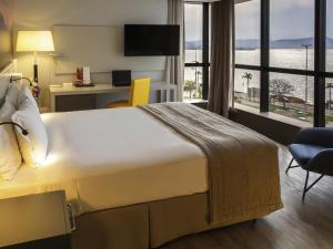 a hotel room with a large bed and a large window at Novotel Florianopolis in Florianópolis