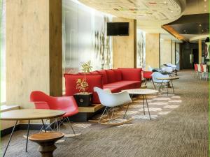 a lobby with a red couch and tables and chairs at Ibis Mexico Perinorte in Mexico City