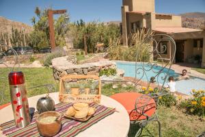 a table in a yard with a pool in the background at Hotel El Reposo Del Diablo in Tilcara