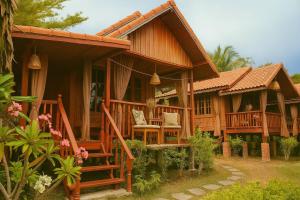 a wooden house with a porch and a balcony at Teak House Lanta-6 Mins Walk To Beach in Ko Lanta