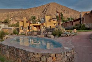a home with a stone wall around a swimming pool at Hotel El Reposo Del Diablo in Tilcara