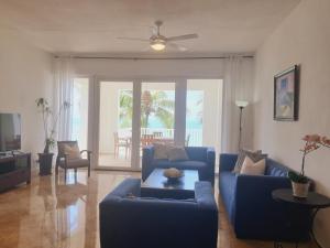 sala de estar con 2 sofás azules y ventilador de techo en Cabarete Beach Palace 3-BDR Condo, en Cabarete