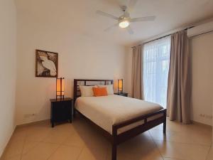 Un dormitorio con una cama con ventilador de techo y una ventana. en Cabarete Beach Palace 3-BDR Condo, en Cabarete