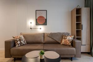 a living room with a brown couch and a table at Przytulne Studio Sikorskiego Balkon i Parking by Noclegi Renters in Kielce