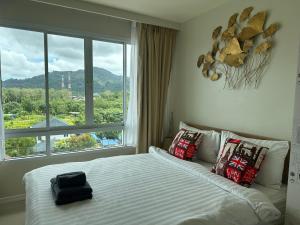 Un dormitorio con una cama con una ventana grande. en Phuket Kathu Pluscondo 37 74, en Kathu