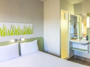 a bedroom with a bed and a sink and a mirror at ibis budget Manchester Salford Quays in Manchester
