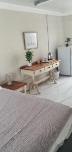 MuizenbergにあるSufi'Sawd Guest Rooms Muizenbergの白い部屋で、デスク、冷蔵庫が備わります。