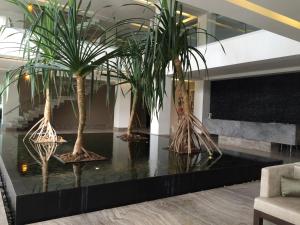 a lobby with three palm trees on a table at La Isla Gran Cayman 904 in Acapulco