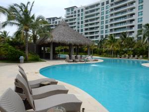 a swimming pool with chairs and a large building at La Isla Gran Cayman 904 in Acapulco