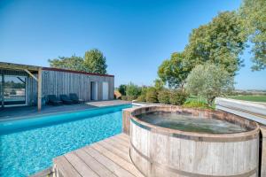 a hot tub on a deck next to a swimming pool at Villa Virginie gite 2 in Faudoas