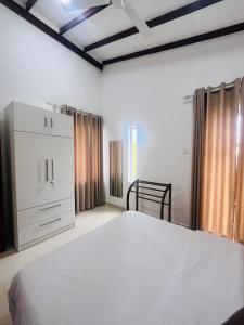 ネゴンボにあるCelestial Negombo Villa 14の白いベッドとドレッサーのある寝室